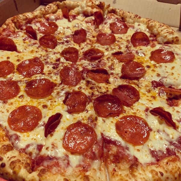 A close-up of a Mr Pizza pepperoni pizza with melted cheese in a cardboard box.