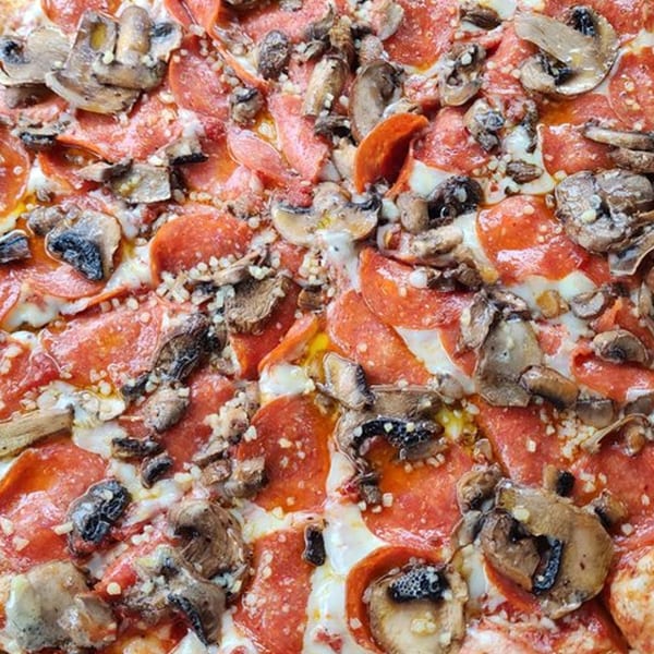 Close-up of a Mr Pizza pepperoni and mushroom pizza with melted cheese.